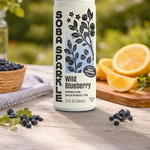 Sparklebuck Wild Blueberry sparkling buckwheat tea can on a wooden table with blueberries and oranges.